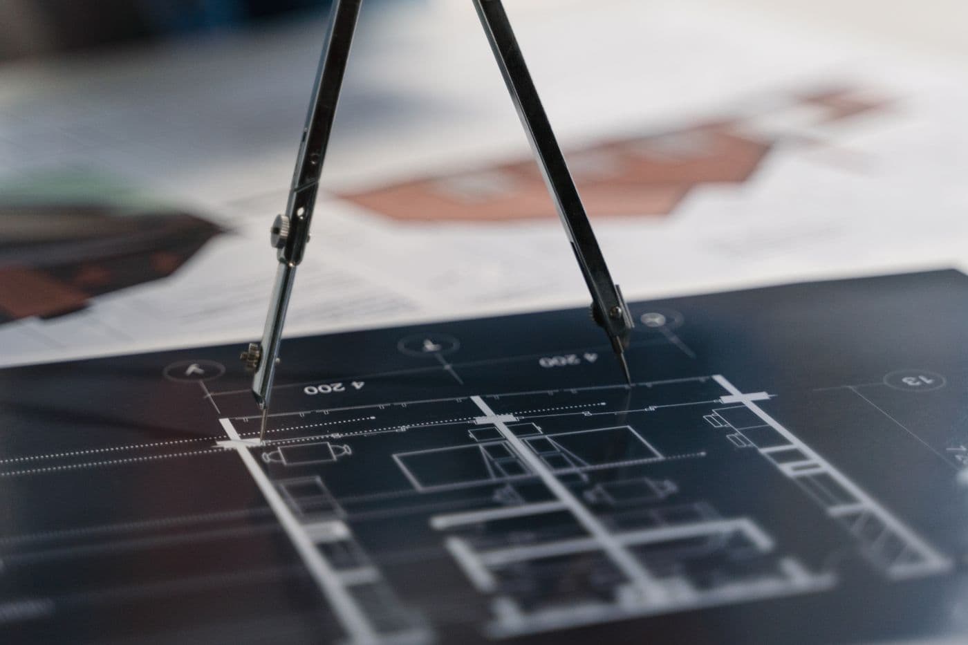 Drafting compass on a dark architectural floor plan